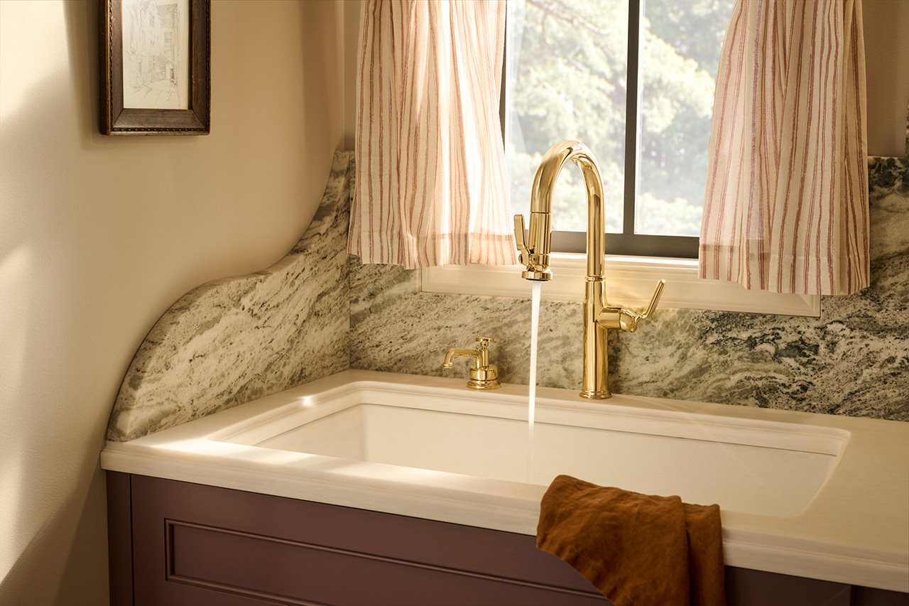 Brizo Unlacquered Brass faucet running water into a white sink.