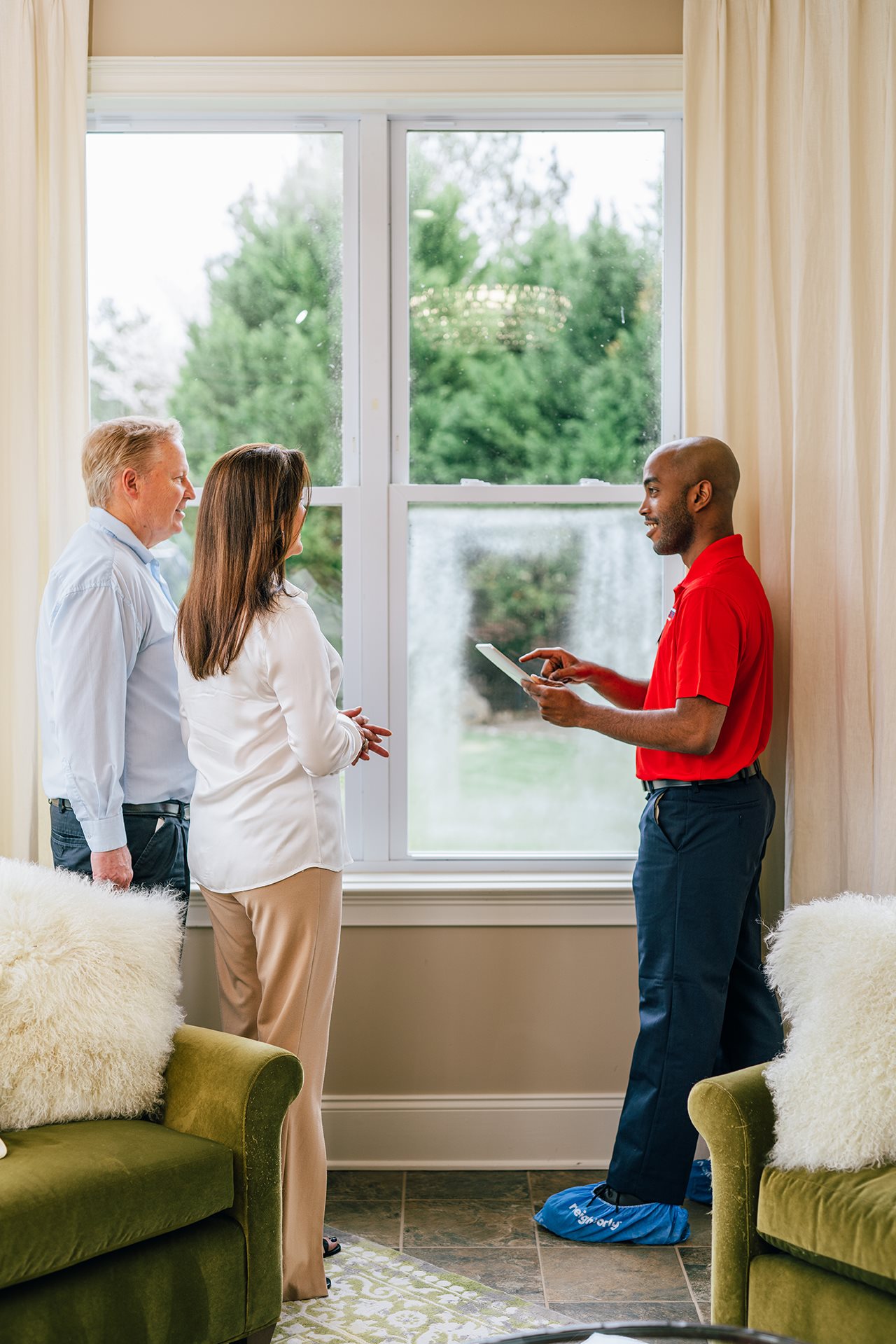 Couple talking with a representative from Glass Doctor about window replacement in their home.