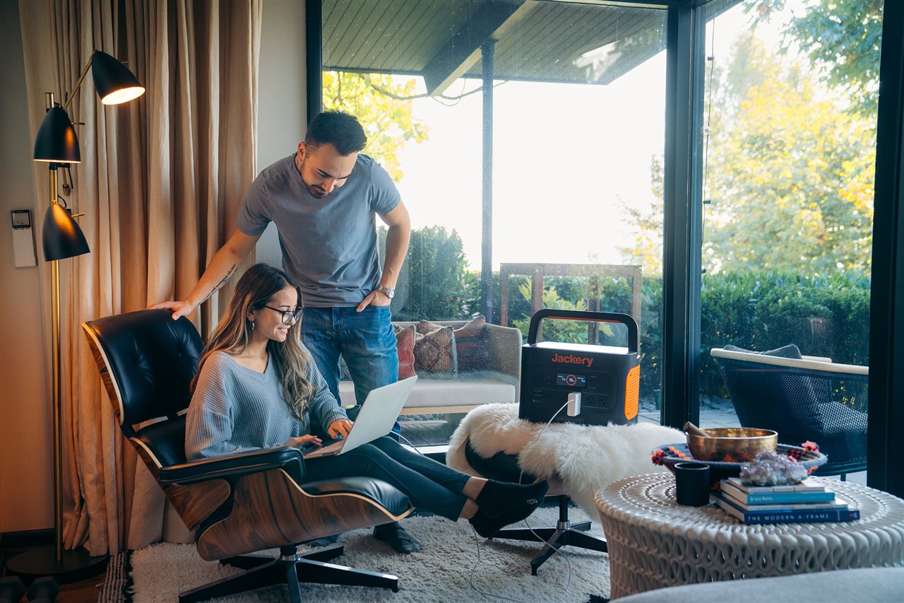 Couple using laptop in living room powered by a Jackery Generator.