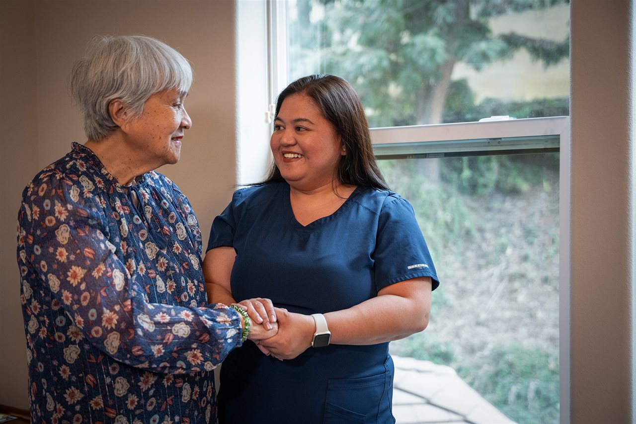 A health care provider from Vivid Life Home Care holding hands and talking with Strela's mother.