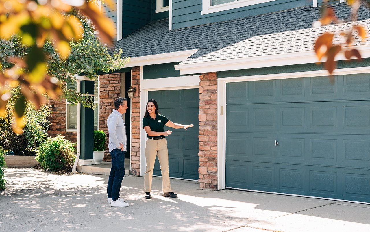 Representative from Precision Garage Door in talking with a homeowner in front of his house.