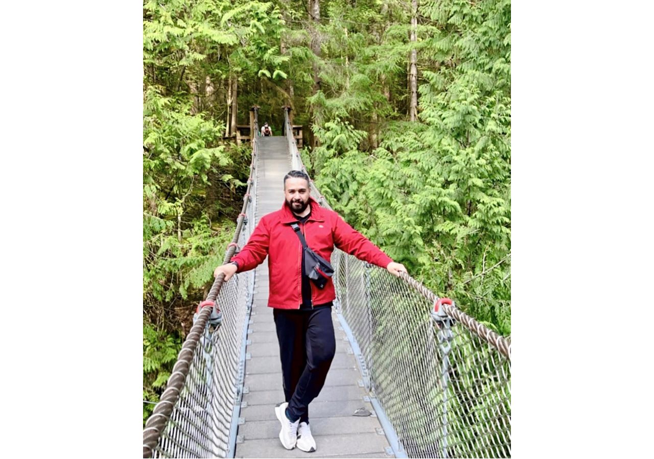 Jimmy poses in the center of a wooden bridge in the woods.