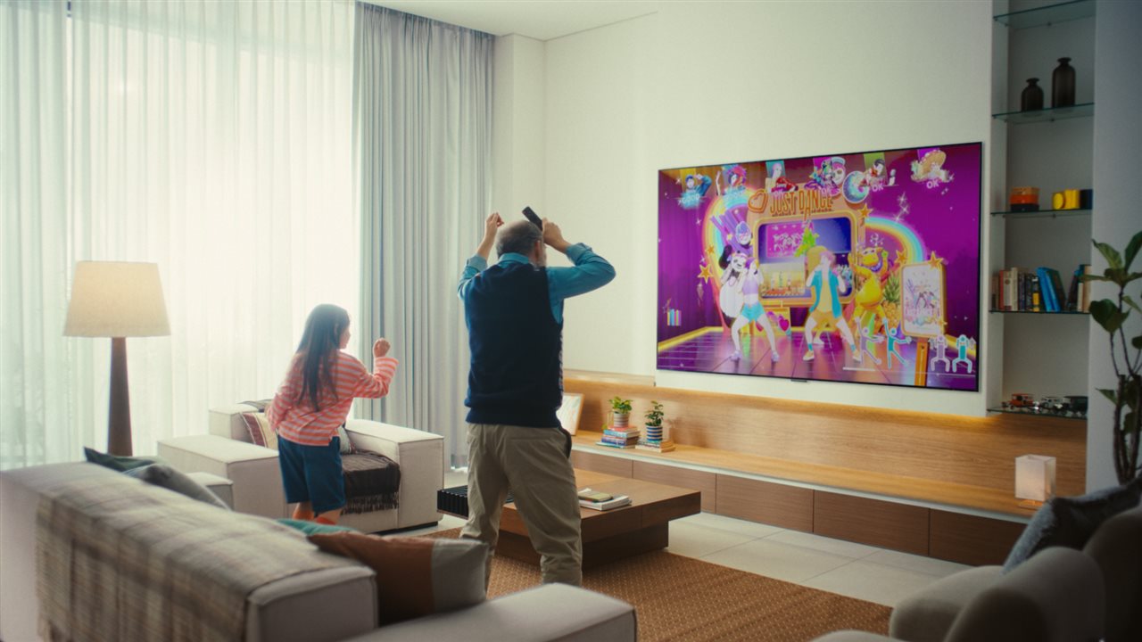 Grandfather and granddaughter playing video games on big screen tv.