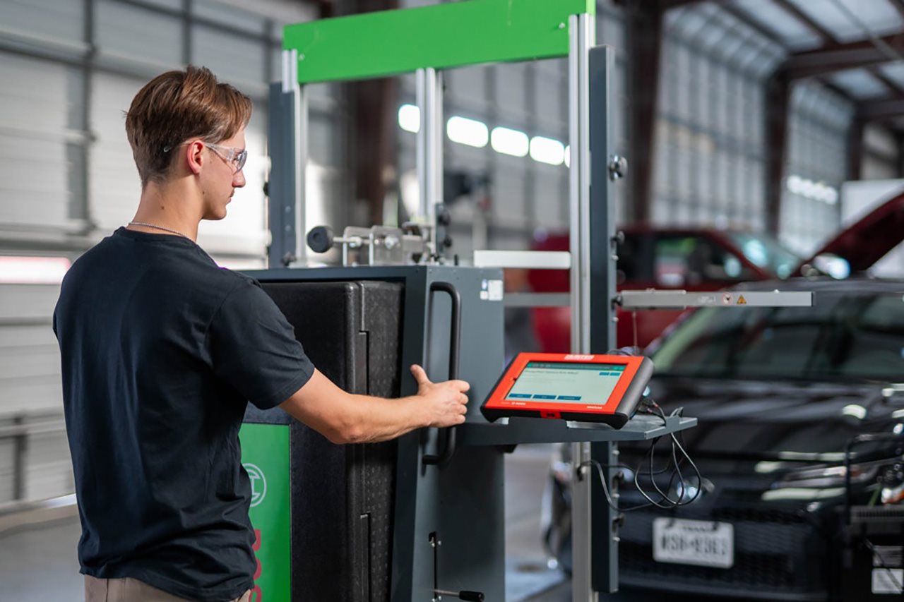 A man works at a computer terminal in a car repair shop.