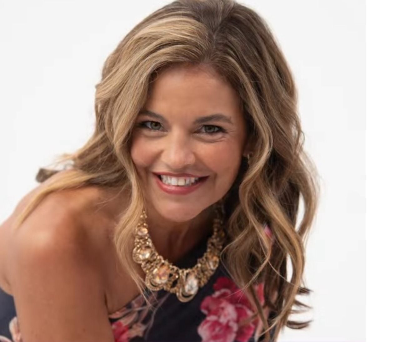 Close-up of smiling Adrianne in a floral dress.
