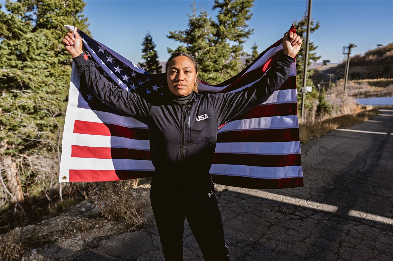 Spc. Azaria Hill, standing with American flag, will be among the 47% of athlete quota spots allocated to women in Milan.