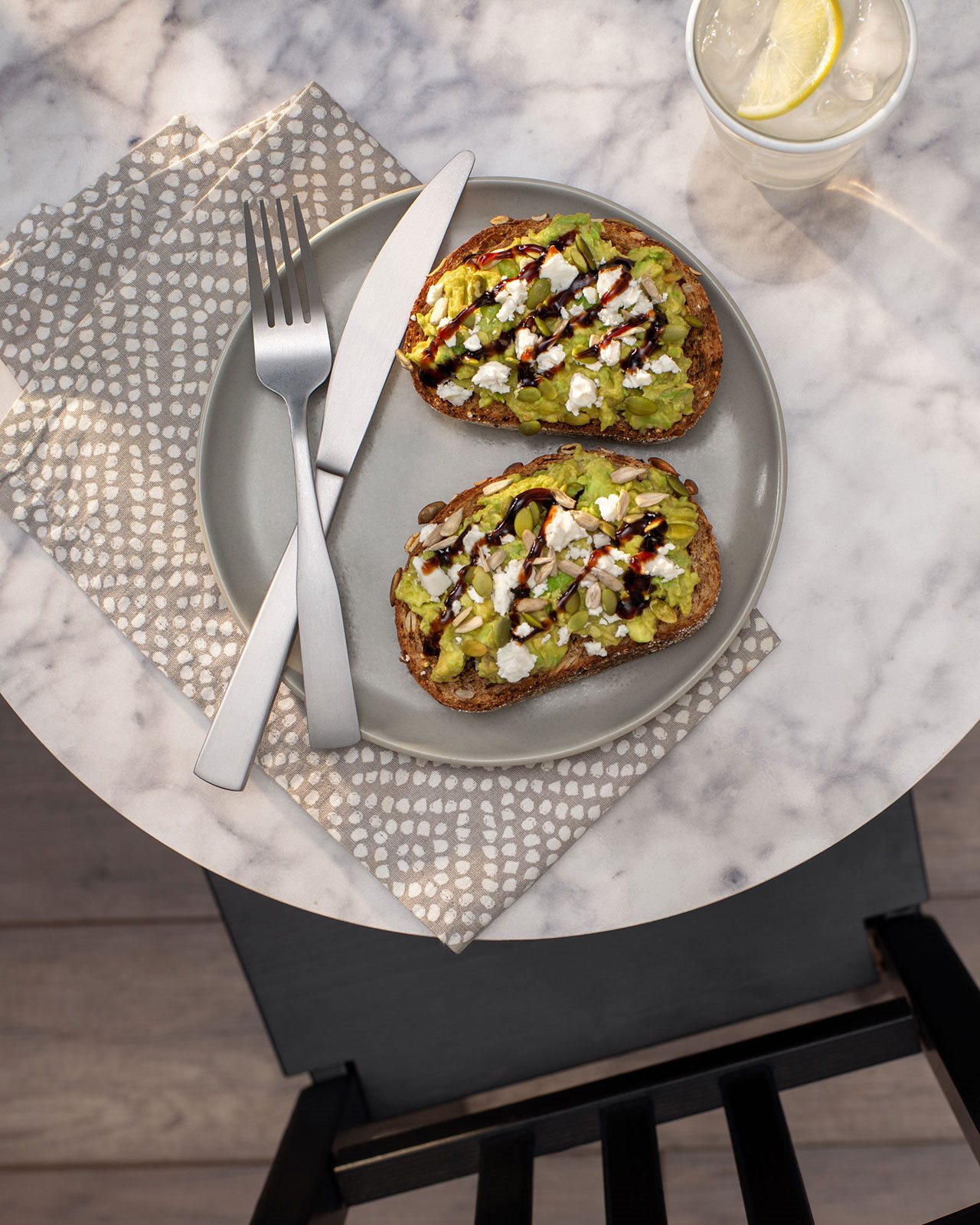 Caprese Avocado on Toast with Balsamic Glaze on a plate with a knife and fork