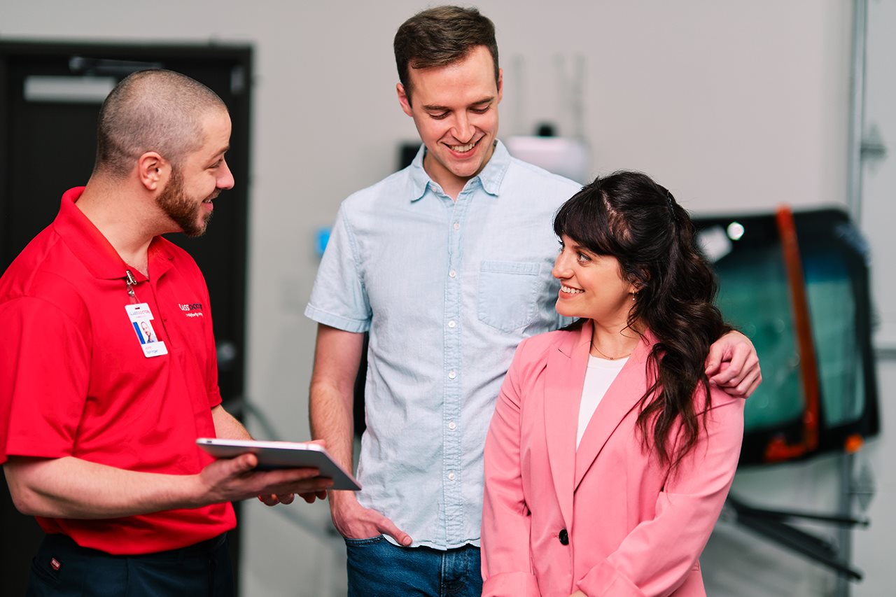Representative from Glass Doctor talking with a couple about their protection program while their car is in the shop.