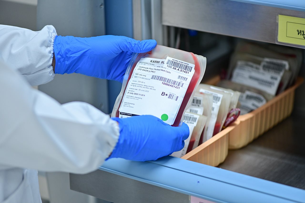 Gloved hands of a lab technician hold a bloodbag.
