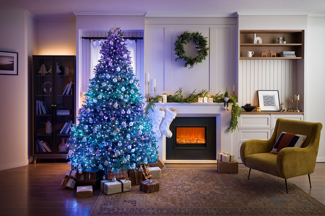 Govee Christmas tree lit with blue, green, and purple lights, next to a fireplace.