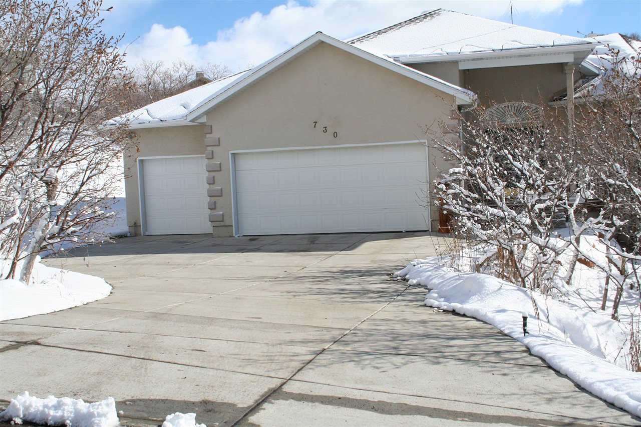 Snow covered house with a clear, dry concrete driveway. Professionals Alliance can help you find a radiant heat installer.