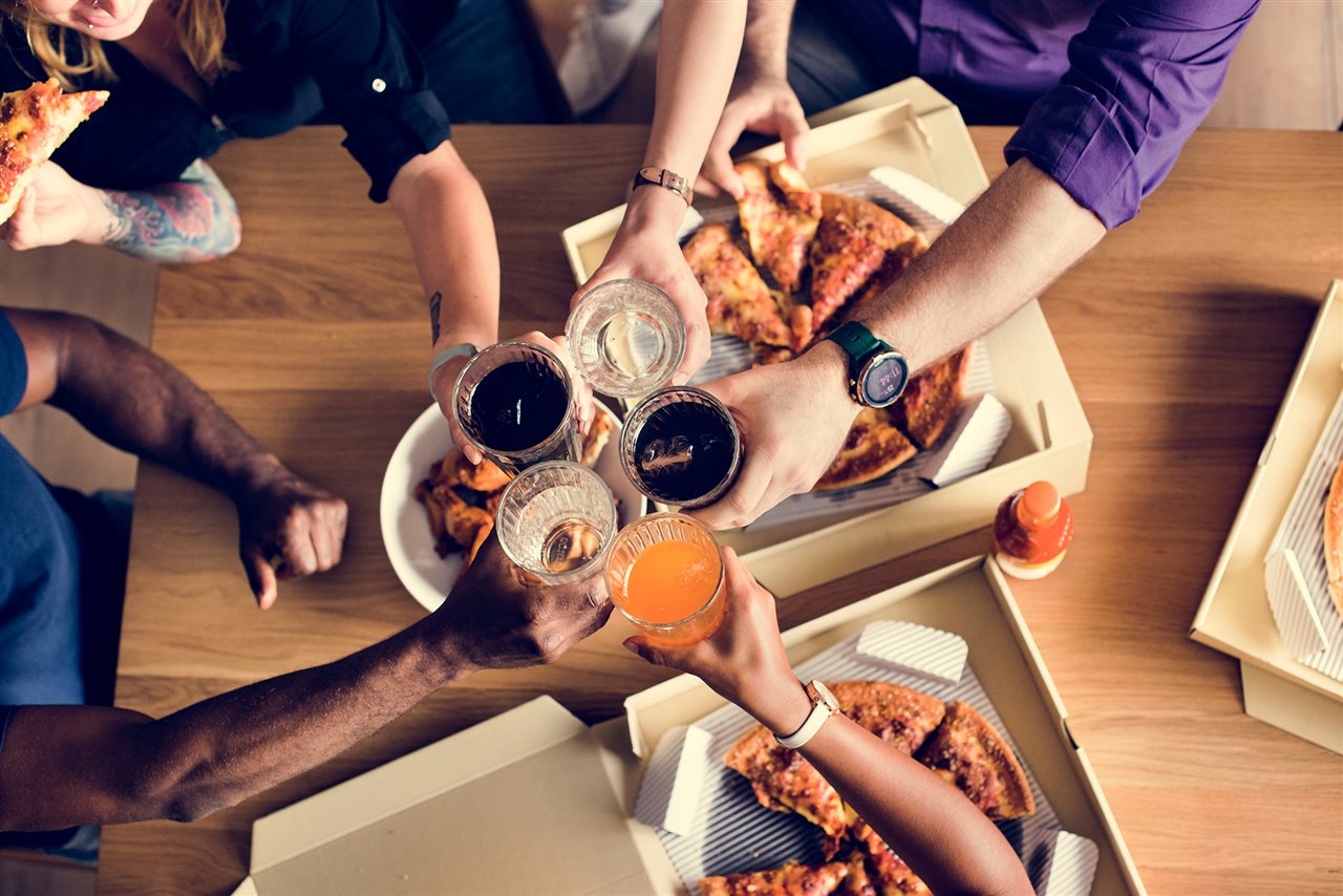 Group of friends enjoy pizza and soft drinks