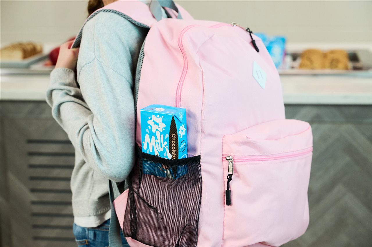 Girl with a TetraPak chocolate milk in her backpack.
