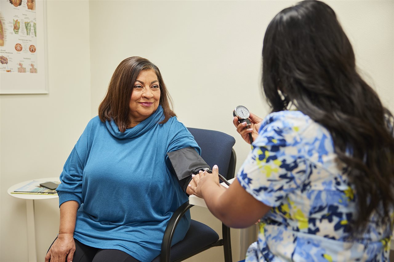Woman in doctor's office having her blood pressure taking by a health care professional