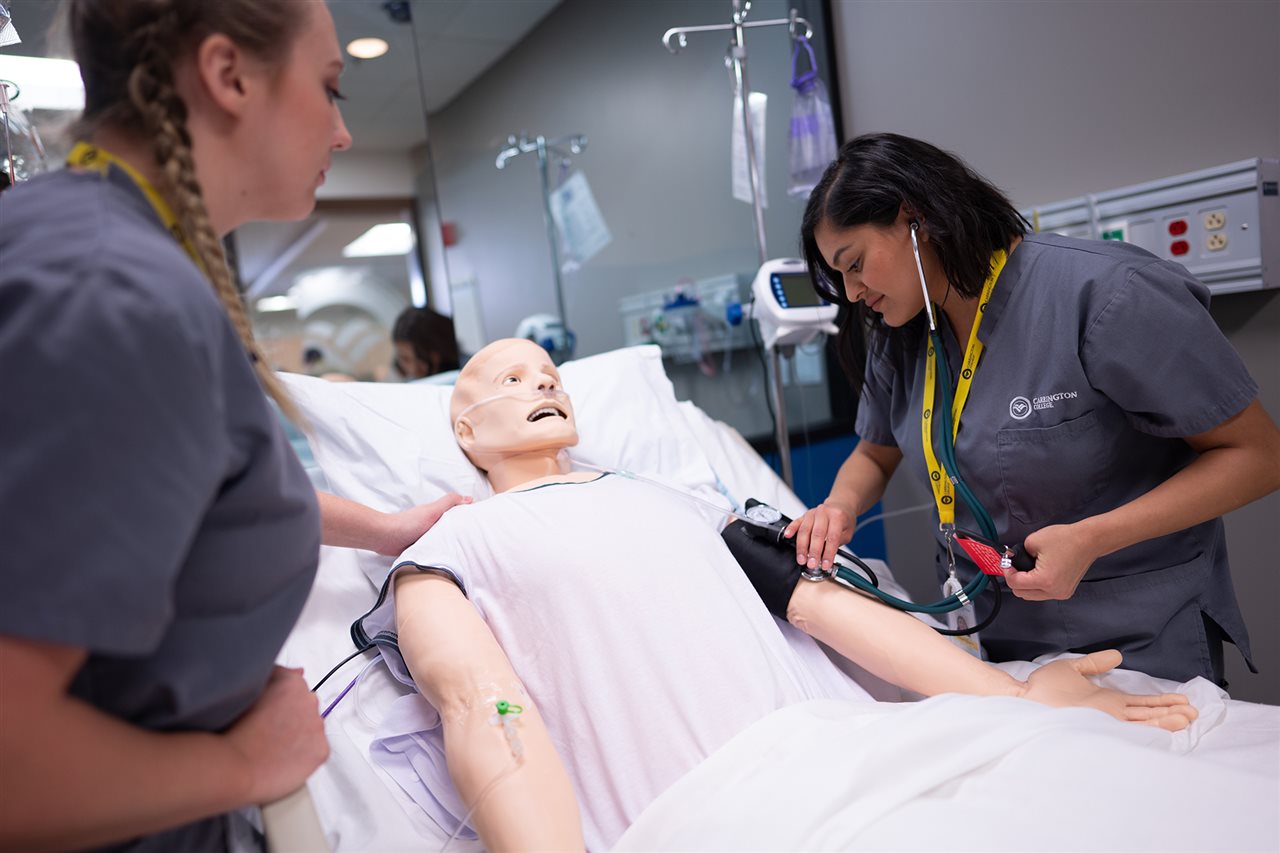 Two nursing students at Carrington taking blood pressure of a patient replica while training.