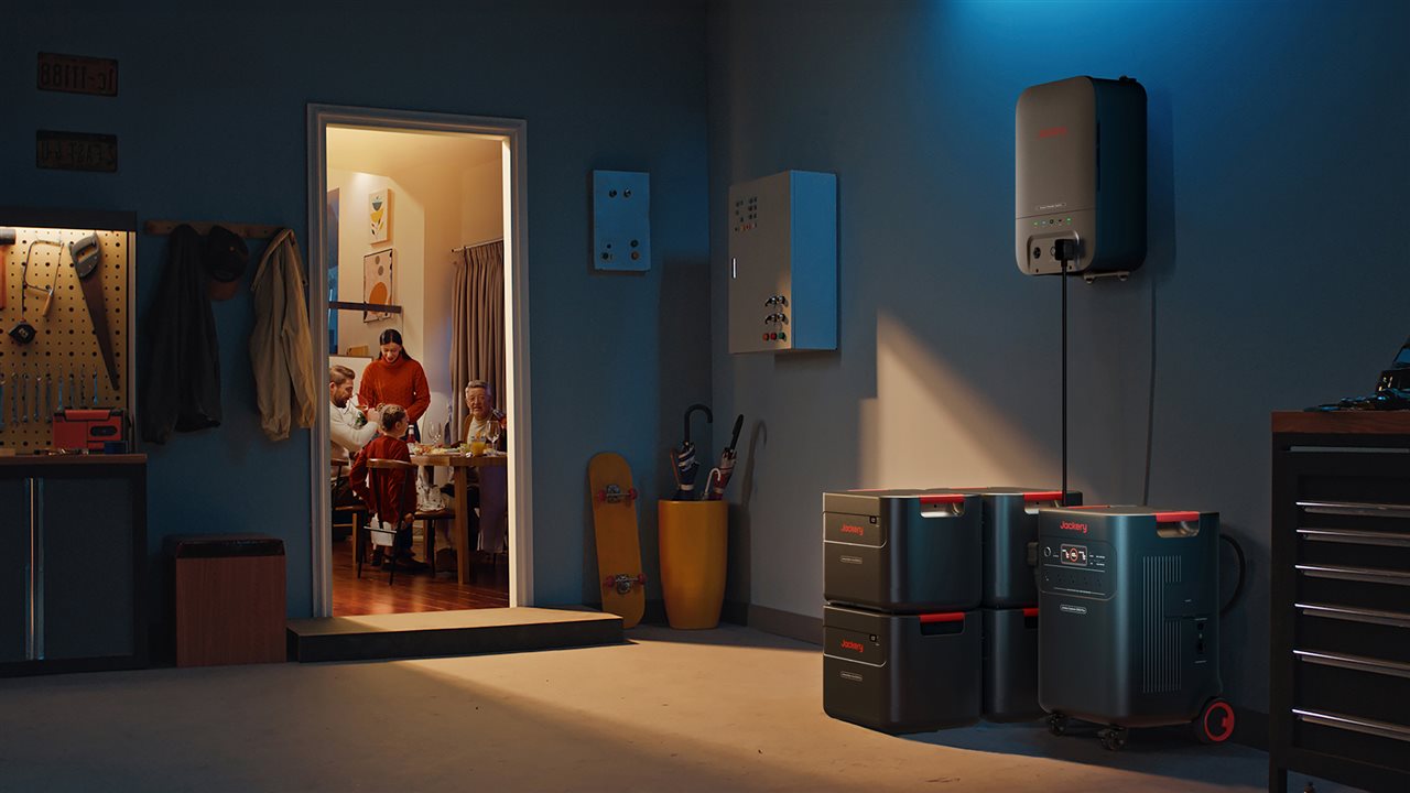 Jackery 5000 home backup system in a garage with a door that leads to a family having dinner in the kichen.
