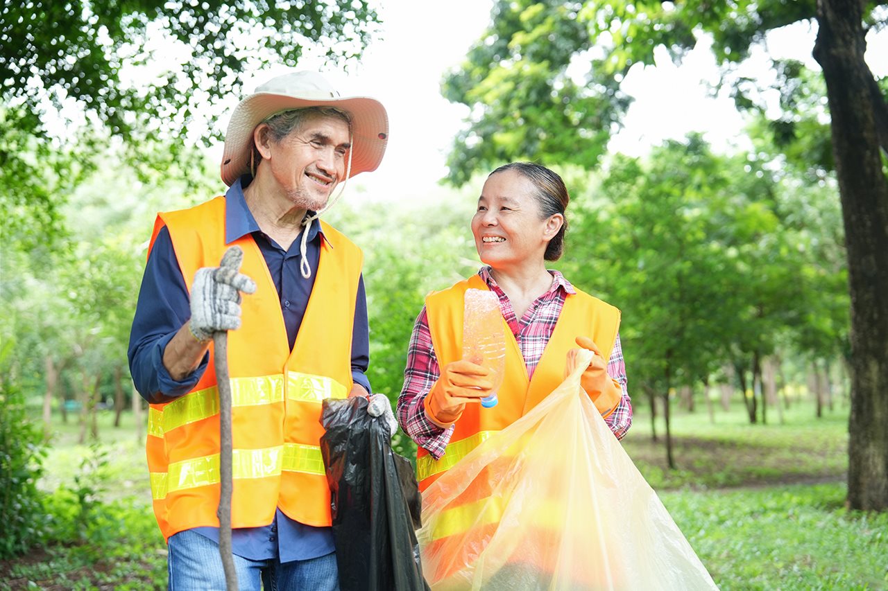 Older couple keeping fit by voluteering and cleaning up a community park