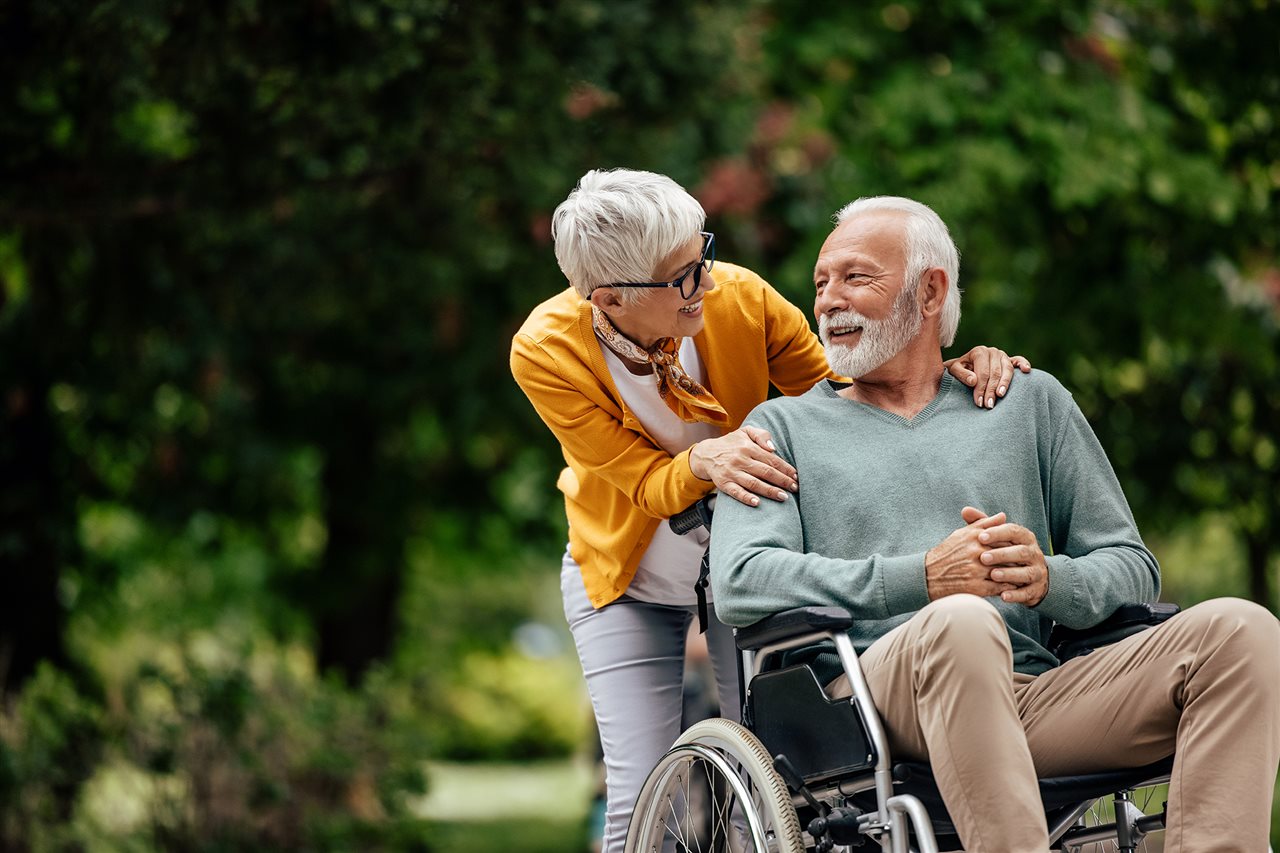 Man in a wheelchair and woman huggin his shoulders.