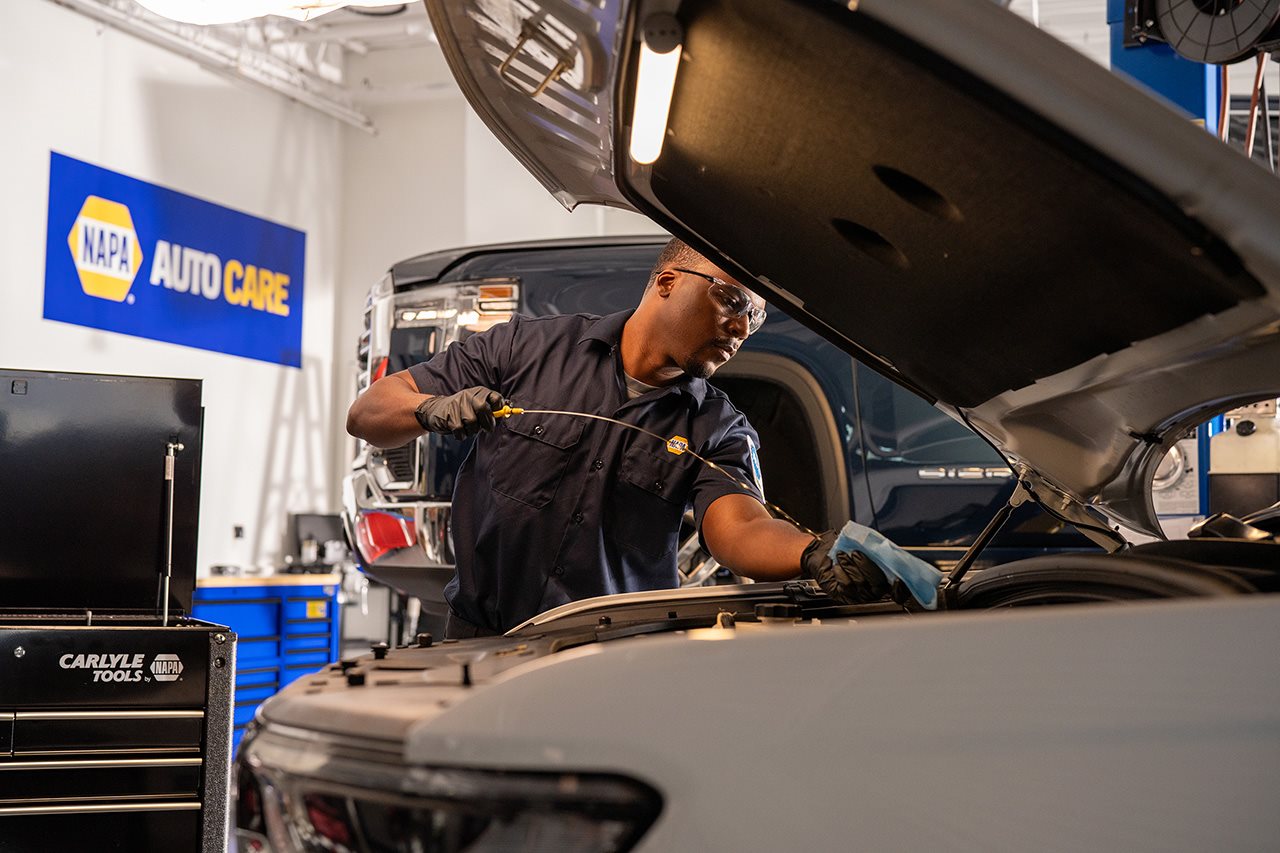 A technician checks the fluid level in a vehicle using a dipstick.