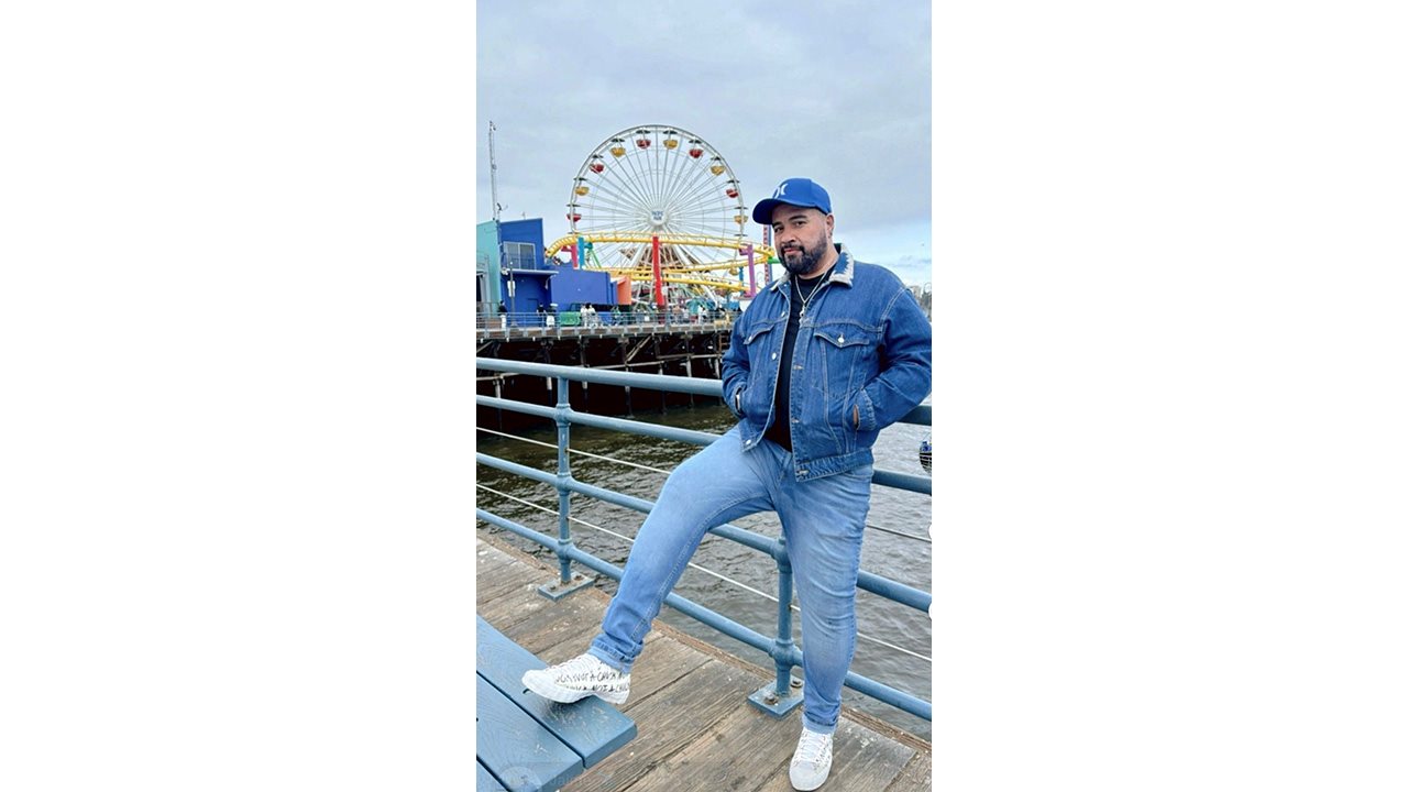 Jimmy leans against a barrier at a boardwalk.