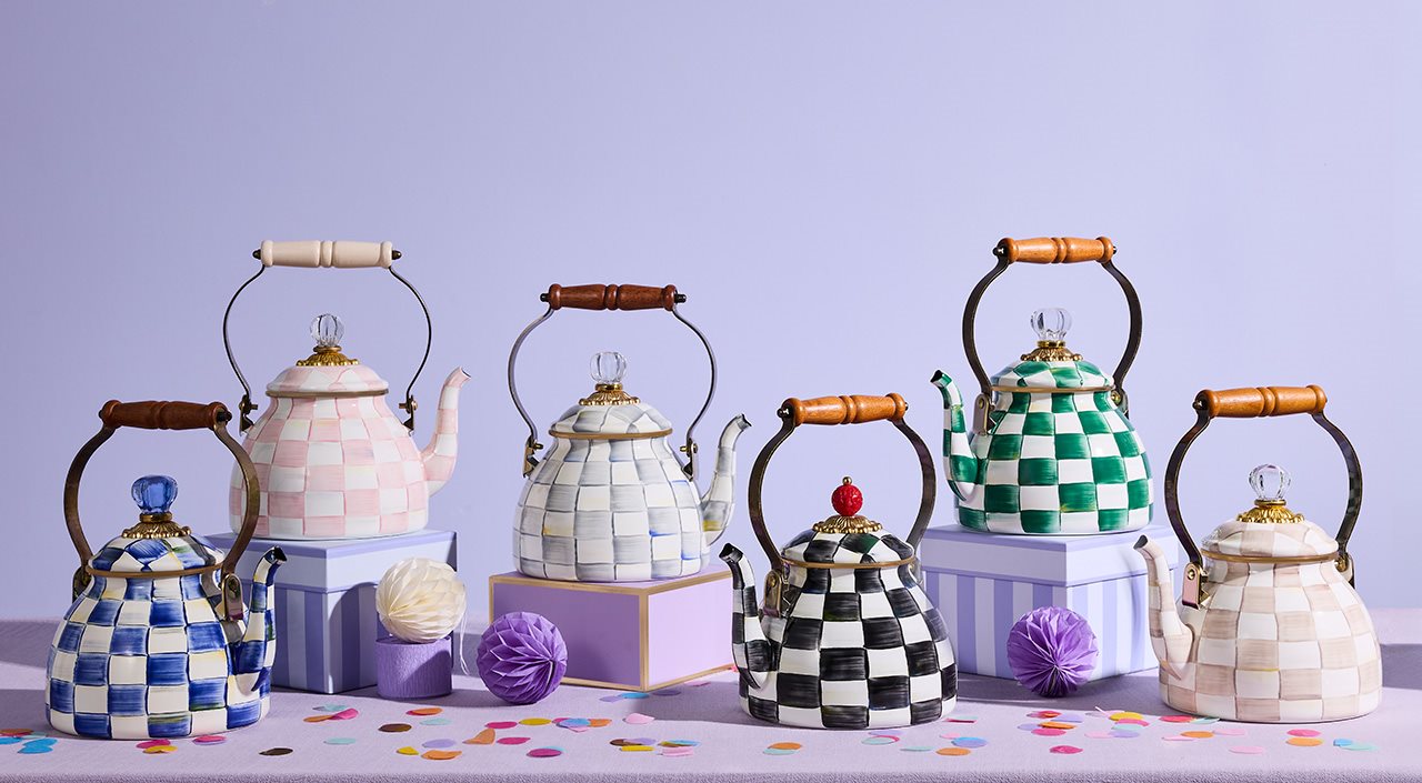 Checkered MacKenzie-Childs tea kettles against a purple backdrop.