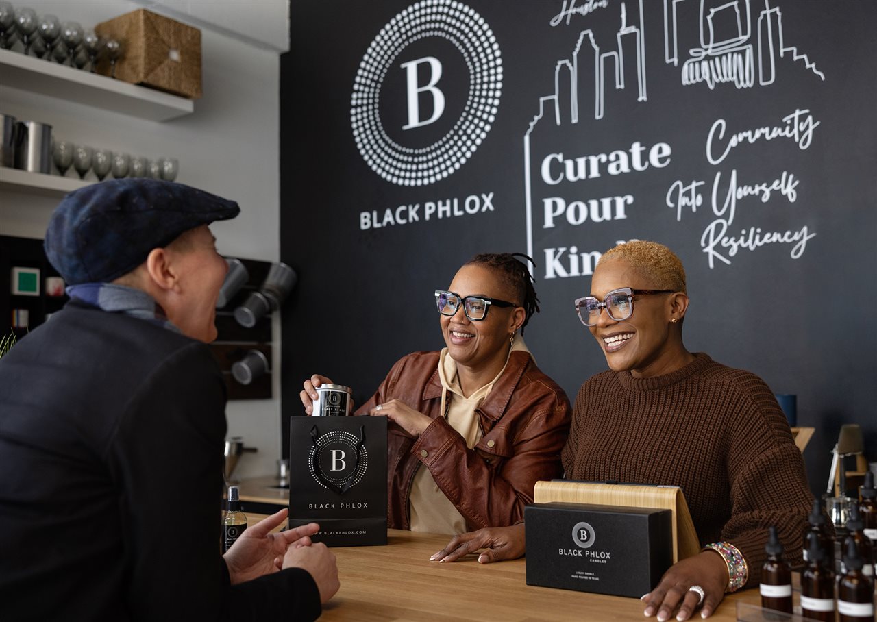 A laughing customer gets their order bagged up at checkout.