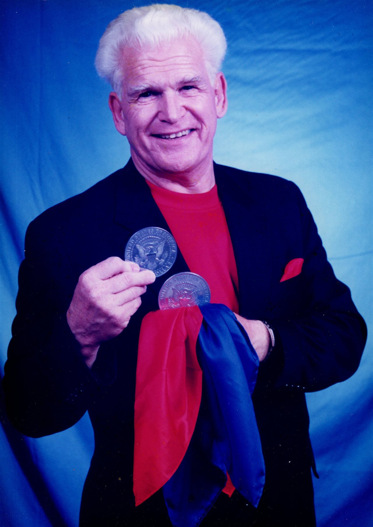 Richard in a blue suit holding giant coins