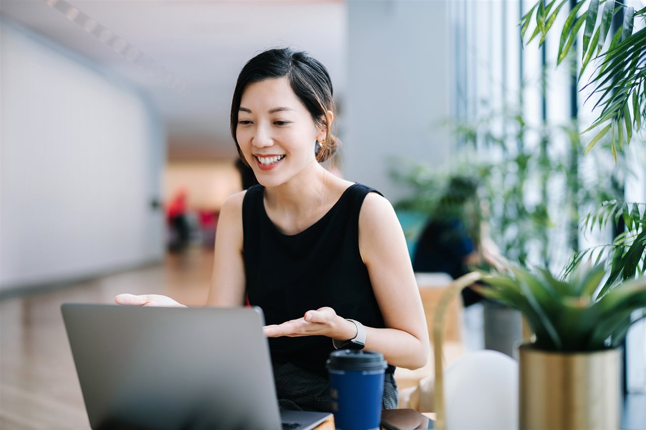 Smiling business owner at laptop in lobby focusing on contacting clients and growing her business.