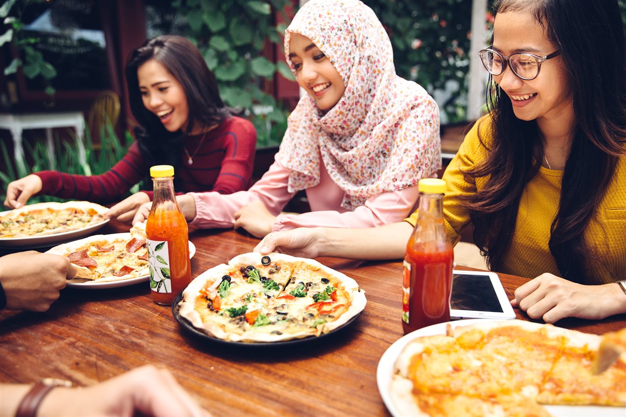 Group of friends enjoy a pizza part outdoors.