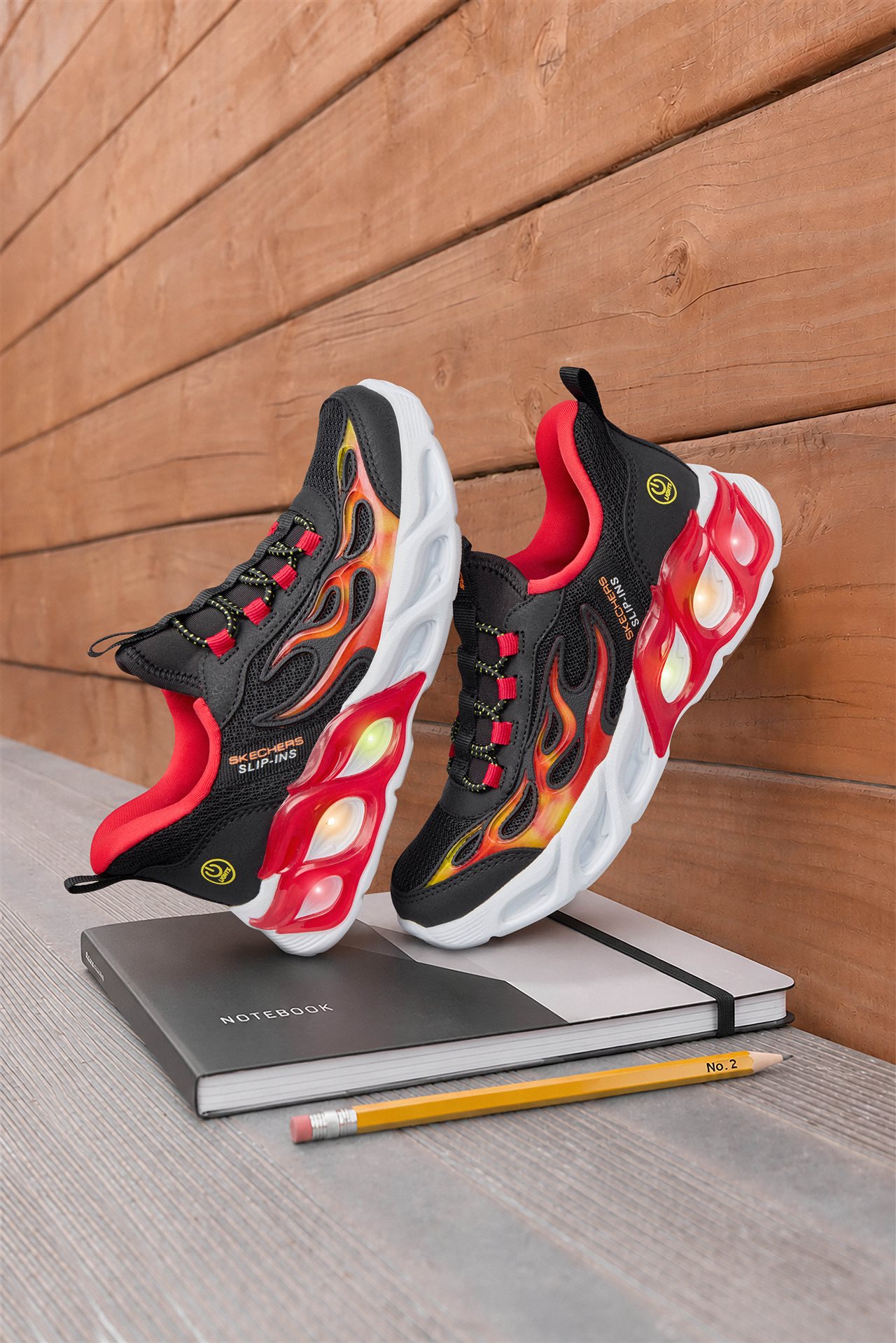 Close-up of a pair of black, red and white Skechers Slip-Ins on top of a notebook.