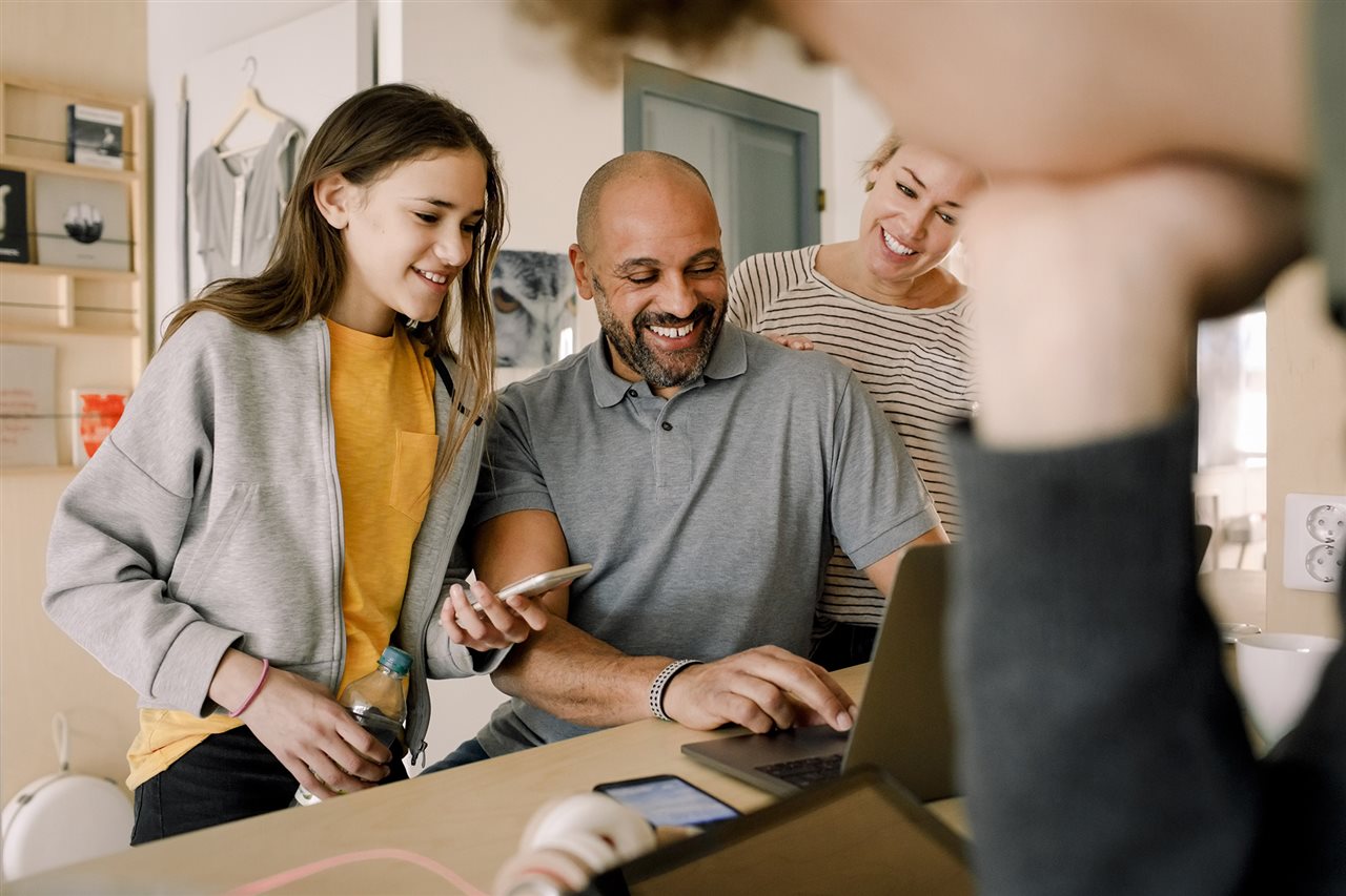 Dad and daughter onlline filling out the FASFA while mom and brother look on.