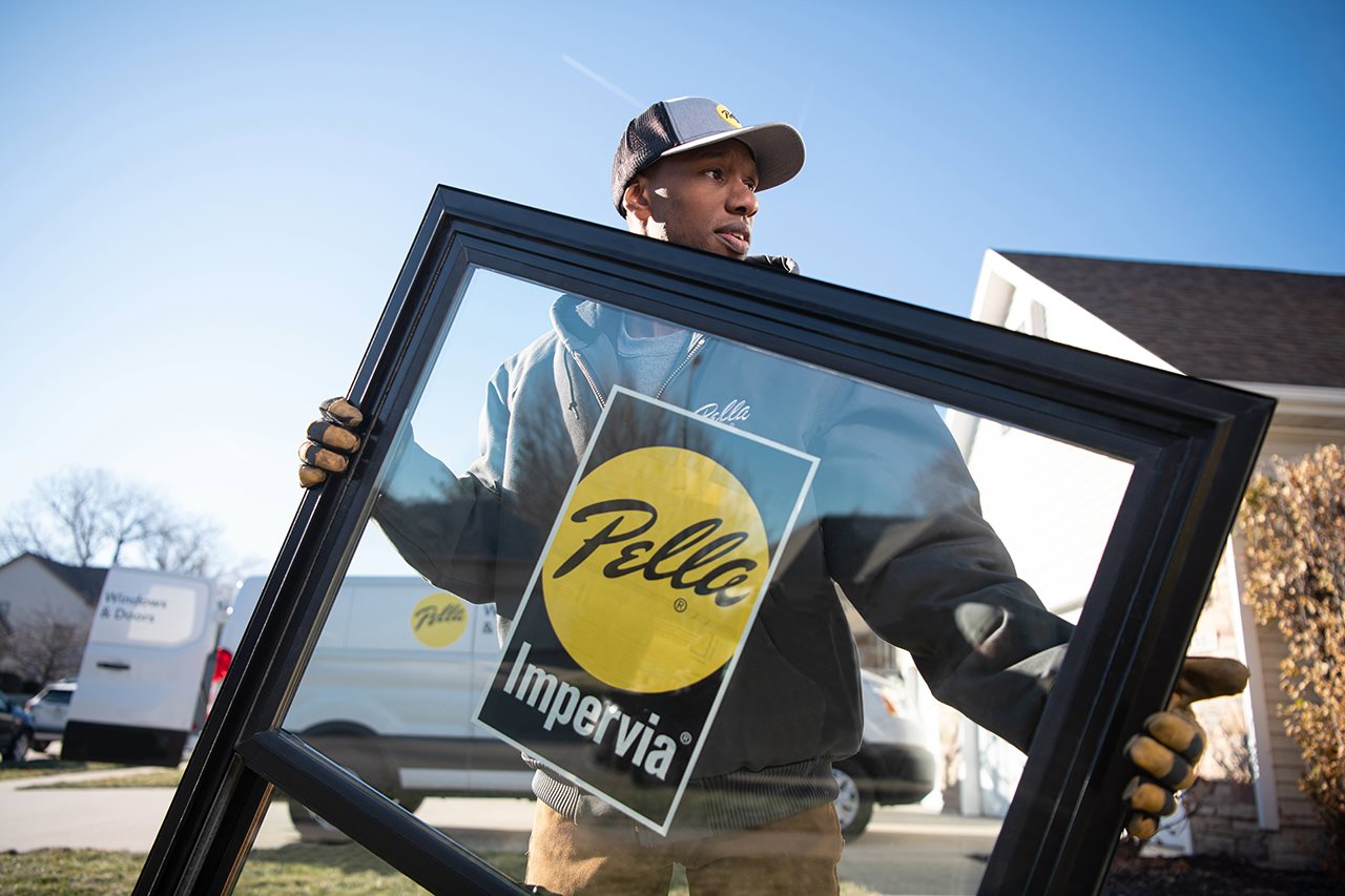 Man moving a pella window in to a home.