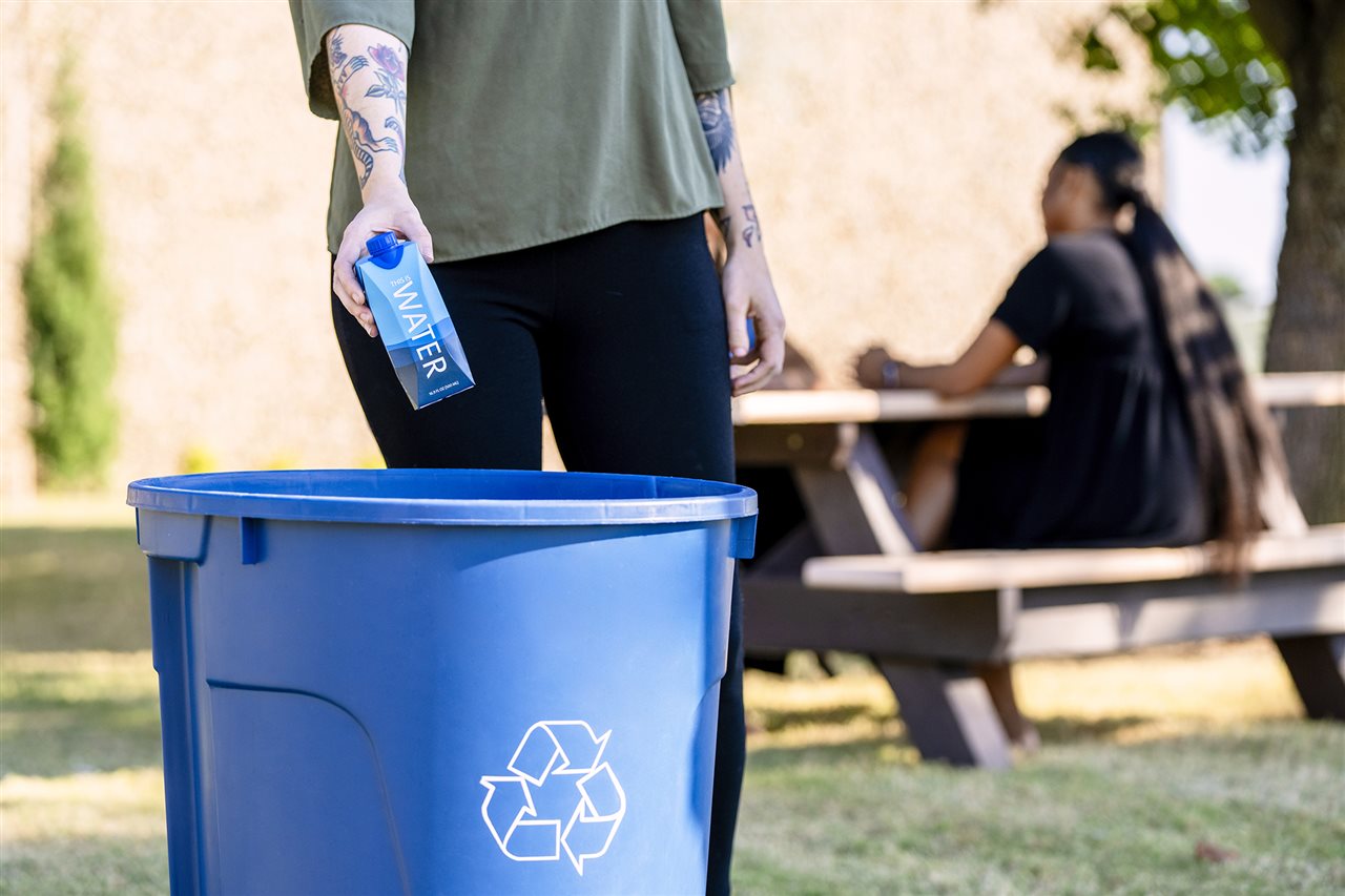 Woman recycling a carton after lunch in the park.