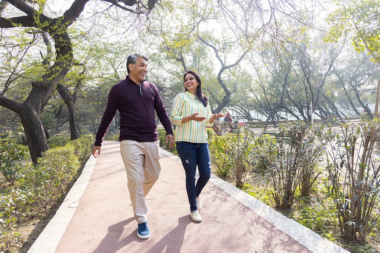Happy couple walking down a path near a beautiful pond on a sunny day.