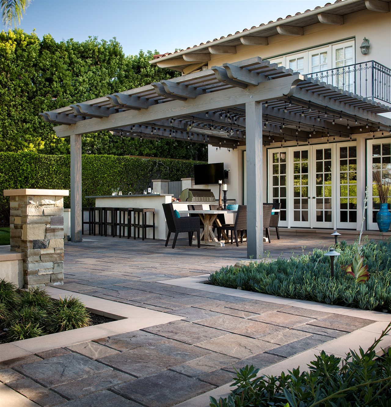 Belgard patio walkway leading to on outdoor kitchen and dining area under a pergola.